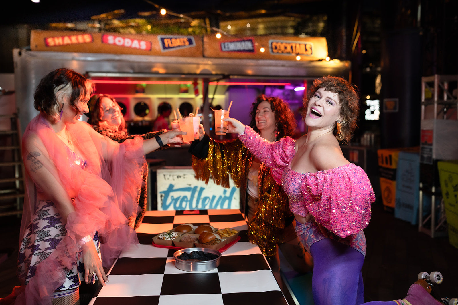 Guests raising cocktails in front of the Trolley’d bar at Neon Dreams during Vivid Sydney 2025