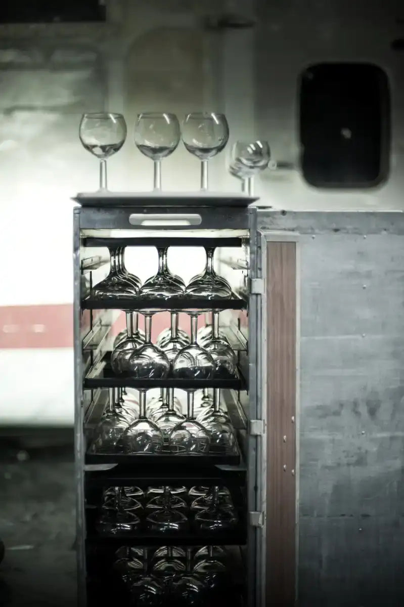 A sleek, multi-tiered wine glass storage cart with a metallic frame and wooden side panel.