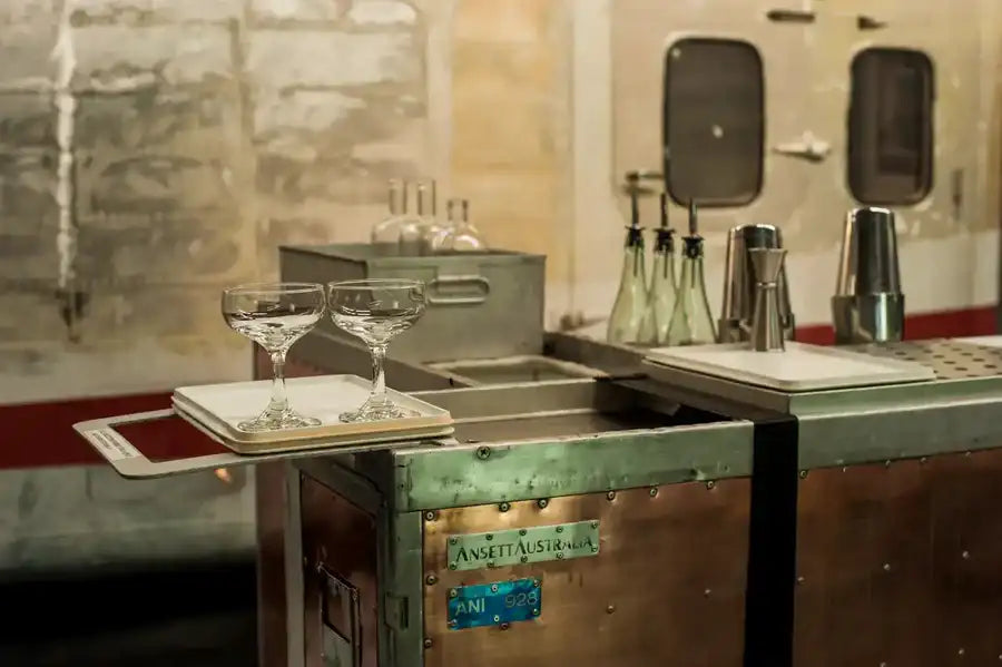 Two clear, stemmed cocktail glasses rest on a white rectangular tray.