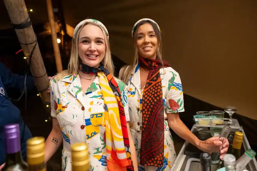 The women are wearing colorful, patterned short-sleeved shirts with a playful tropical and graphic design.
