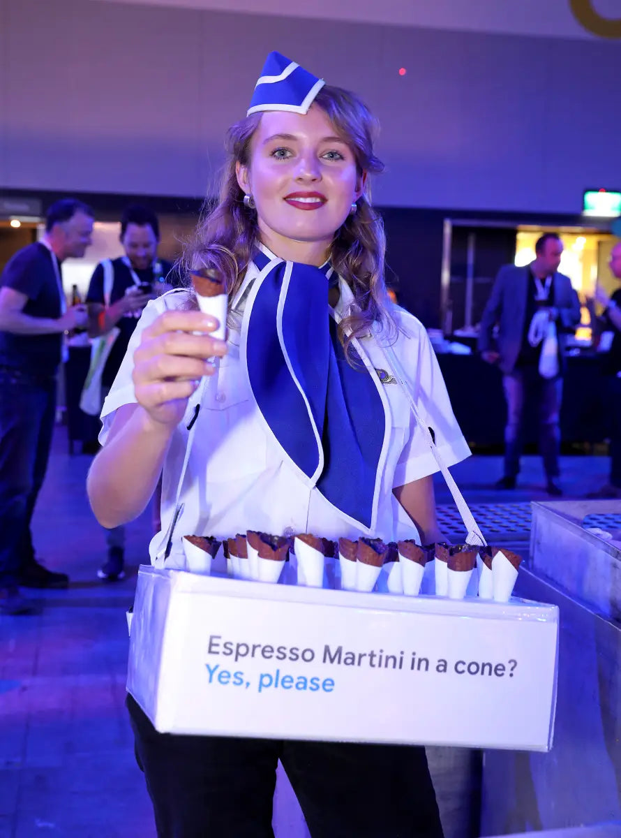 Server in blue and white uniform with espresso martinis showcasing mobile bar hire trends.