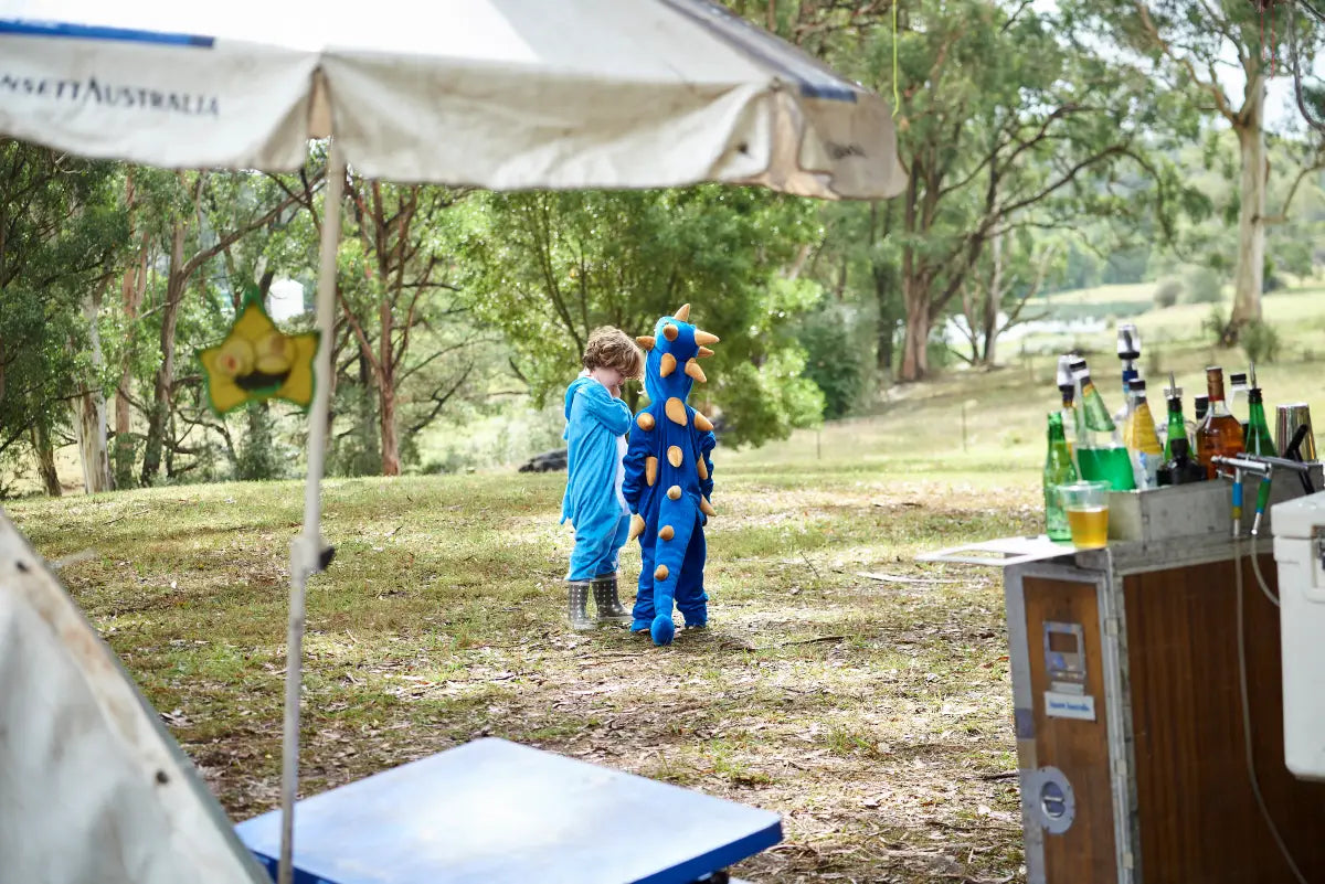 Two children dressed in adorable costumes play near the Trolley'd bar at JP and PG's wedding in Wild Ducks, Southern Highlands. The charming outdoor setting and playful atmosphere highlight the family-friendly and joyous nature of the celebration.