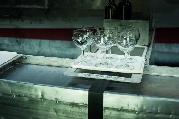 A close-up of a vintage trolley setup by Trolley'd featuring a tray of empty wine glasses and bottles, ready for a stylish event.