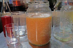 Milk punch mixture undergoing separation, with visible curds forming during the clarification process.