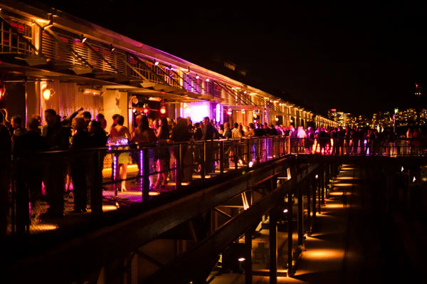 Guests enjoying the nighttime festivities at the Australian Bartender Awards 2023, with vibrant lighting and a lively atmosphere on a waterfront venue