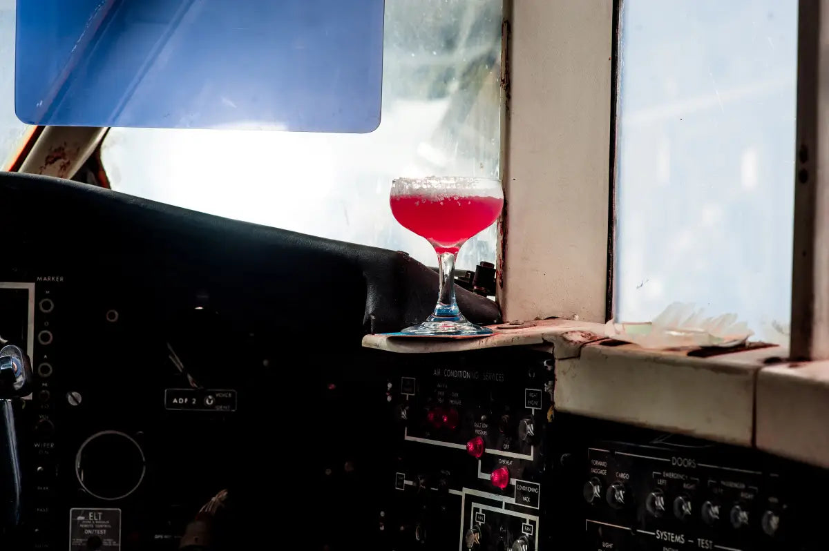 A striking Riberry cocktail garnished with sugar on the rim, placed in the cockpit of an airplane, blending aviation themes with culinary creativity.