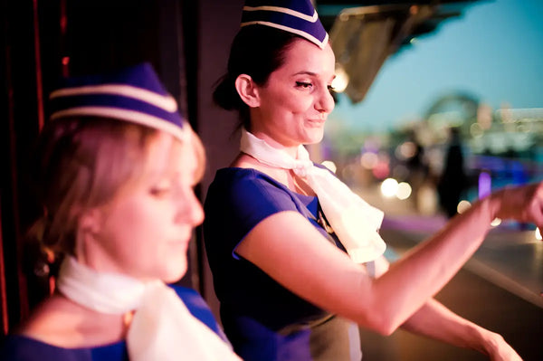 Trolley'd servers in vintage airline-themed uniforms at the Australian Bartender Awards 2023, with a cityscape in the background.