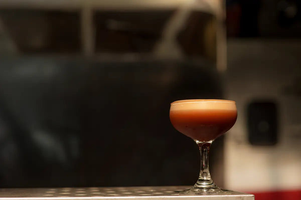 A Trolley'd mocktail served in a coupe glass, featuring a rich and frothy top layer, set against a dimly lit background. The elegant presentation highlights the sophistication and craftsmanship of Trolley'd's mocktail offerings.