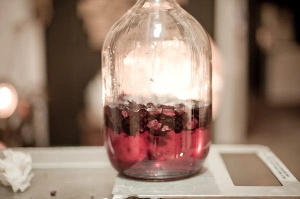 A large glass jar filled with wild berries infusing in alcohol, highlighting the natural and vibrant infusion process at Trolley'd, set against a blurred background.