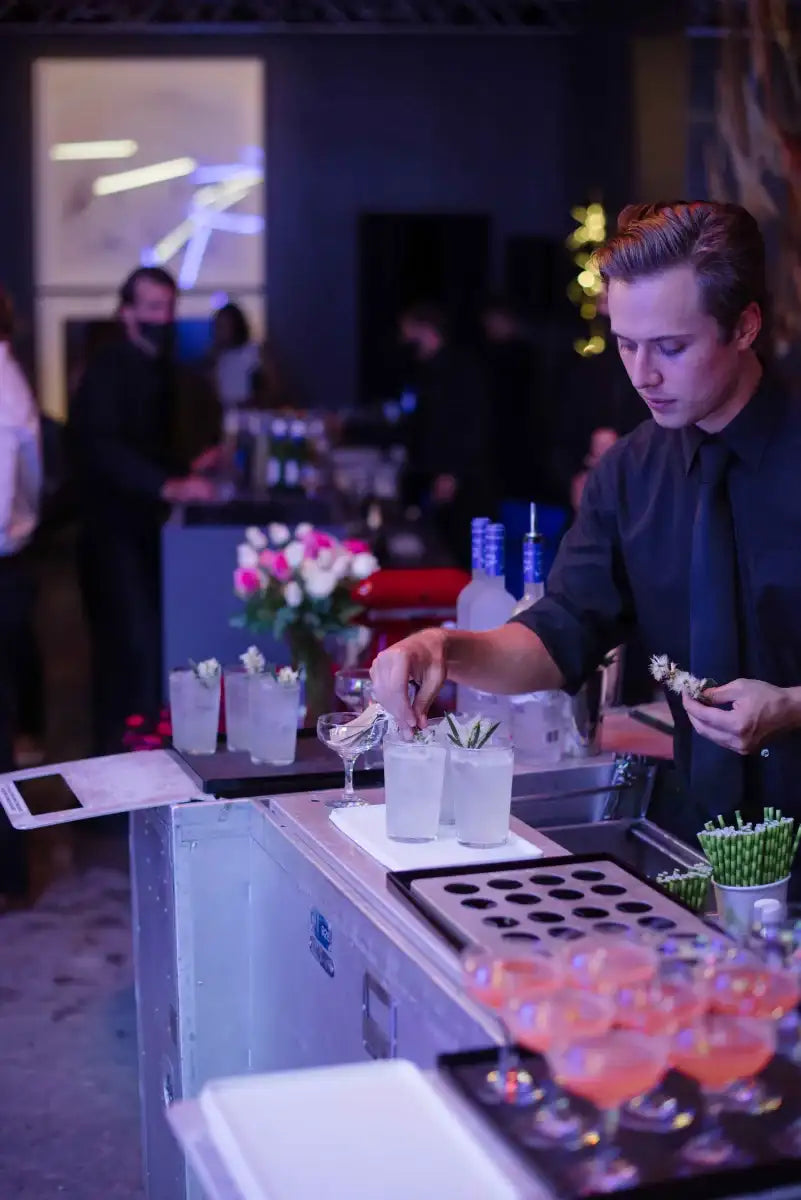 A Trolley’d bartender garnishes cocktails with native ingredients at a corporate event, showcasing sustainable bar services for workplace events.