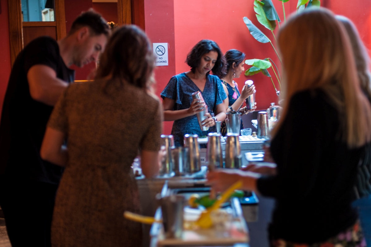 Guests mixing cocktails together at a Trolley’d class around an indoor table