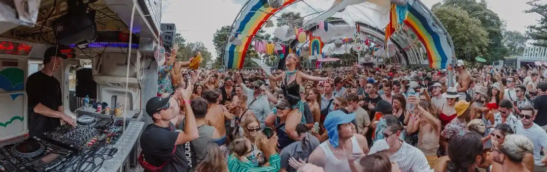 DJ energizing a large crowd at a vibrant festival, with colorful decorations and a lively atmosphere, highlighting Trolley'd top-tier DJ and disc jockey services for events.