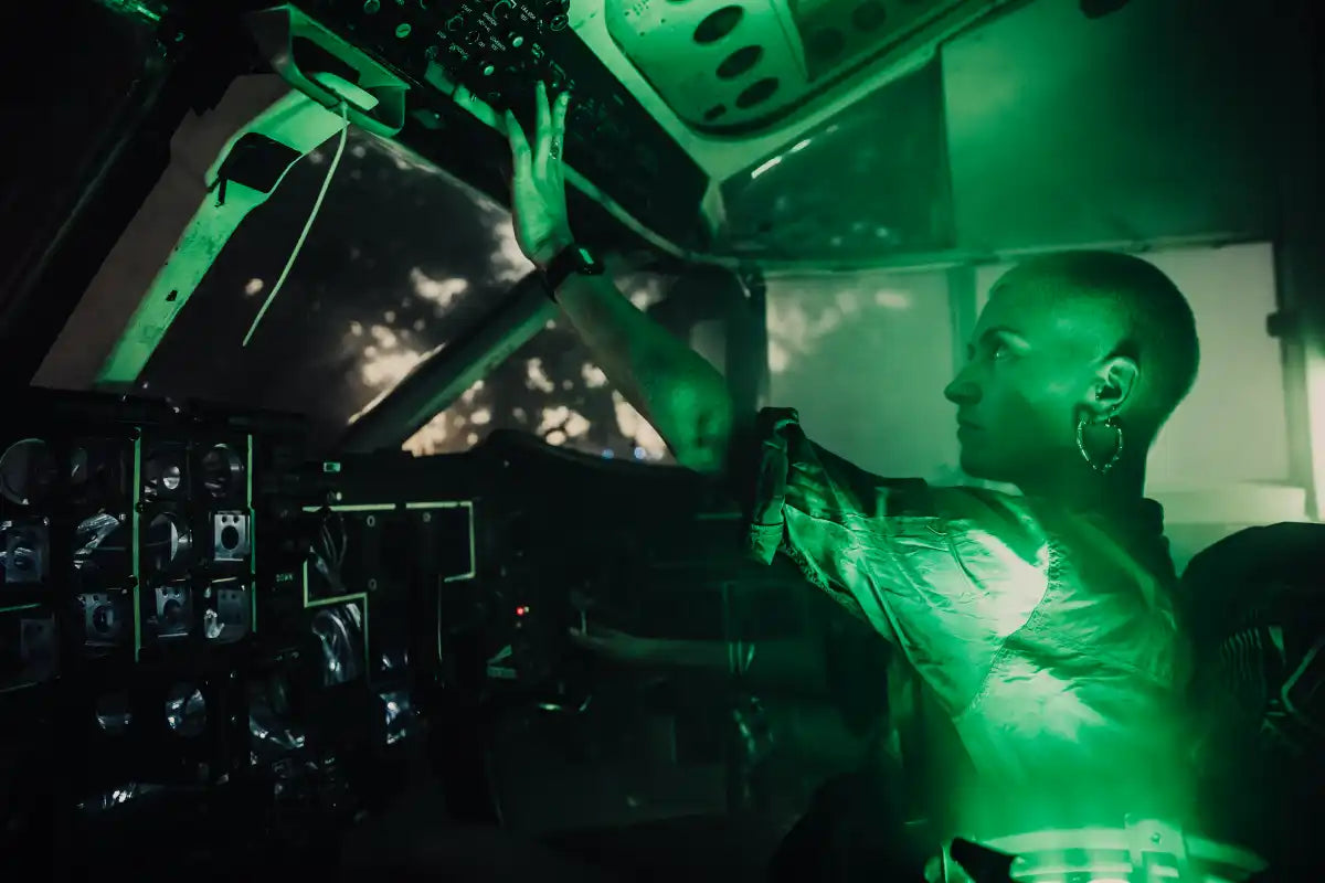 A festival attendee interacts with the controls in the cockpit of the Trolley'd Shorts 330 airplane. Bathed in green LED lighting, this immersive experience highlights the reconditioned aircraft's role as a unique stage and attraction at music festivals and brand activations across Australia.