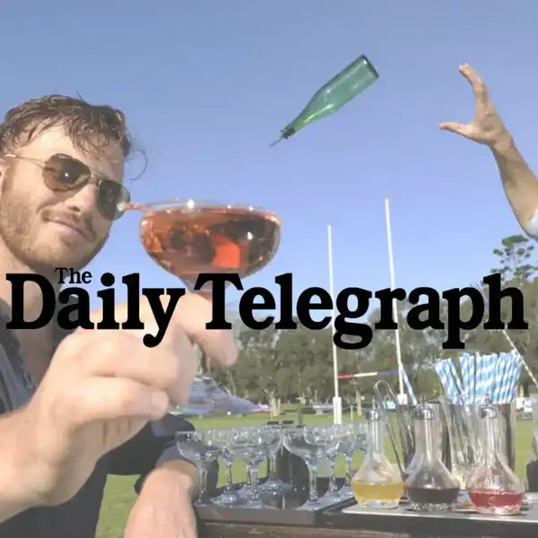 A green glass bottle suspended in mid-air against a clear blue sky.