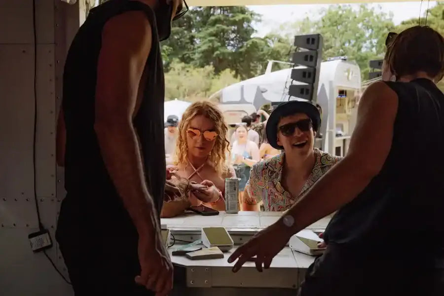 A man wearing a black hat and sunglasses, with a patterned shirt.