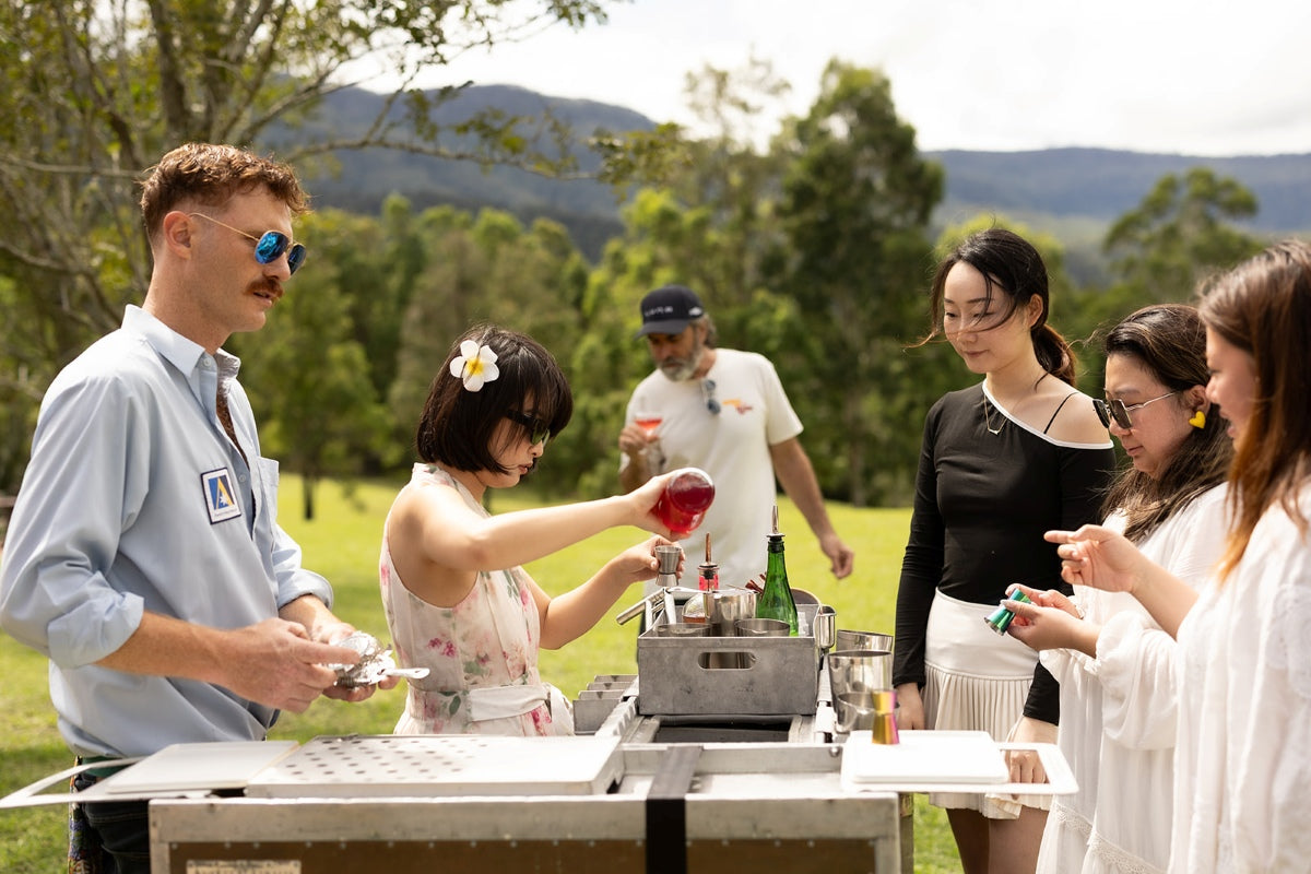 Guests making botanical cocktails together around airline trolley bars outdoors in the Southern Highlands