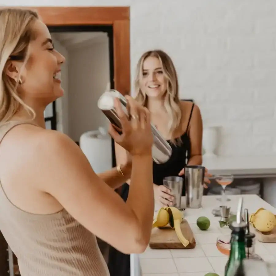 Shiny stainless steel cocktail shaker held in a woman’s hand.