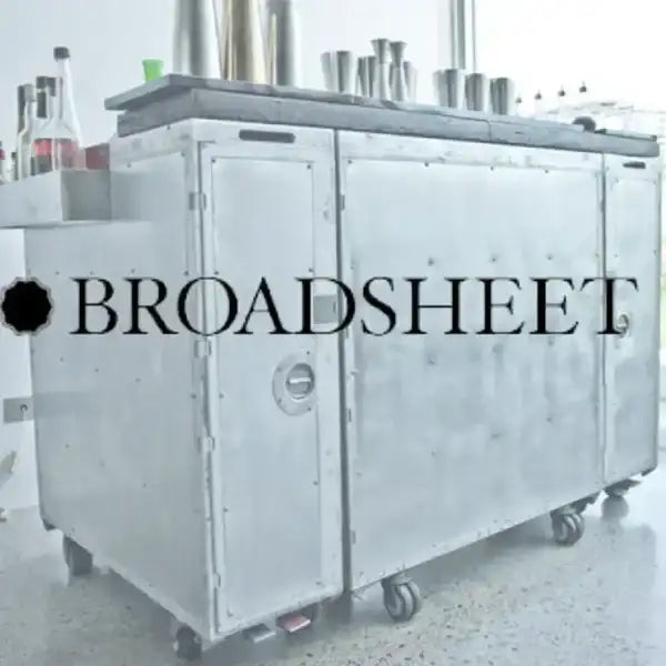 Silver metallic bar cart with riveted panels and black wheels.