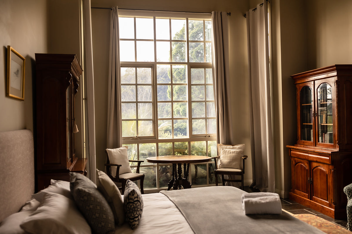 A light-filled room at Lake David with a bed and seating beside a tall window